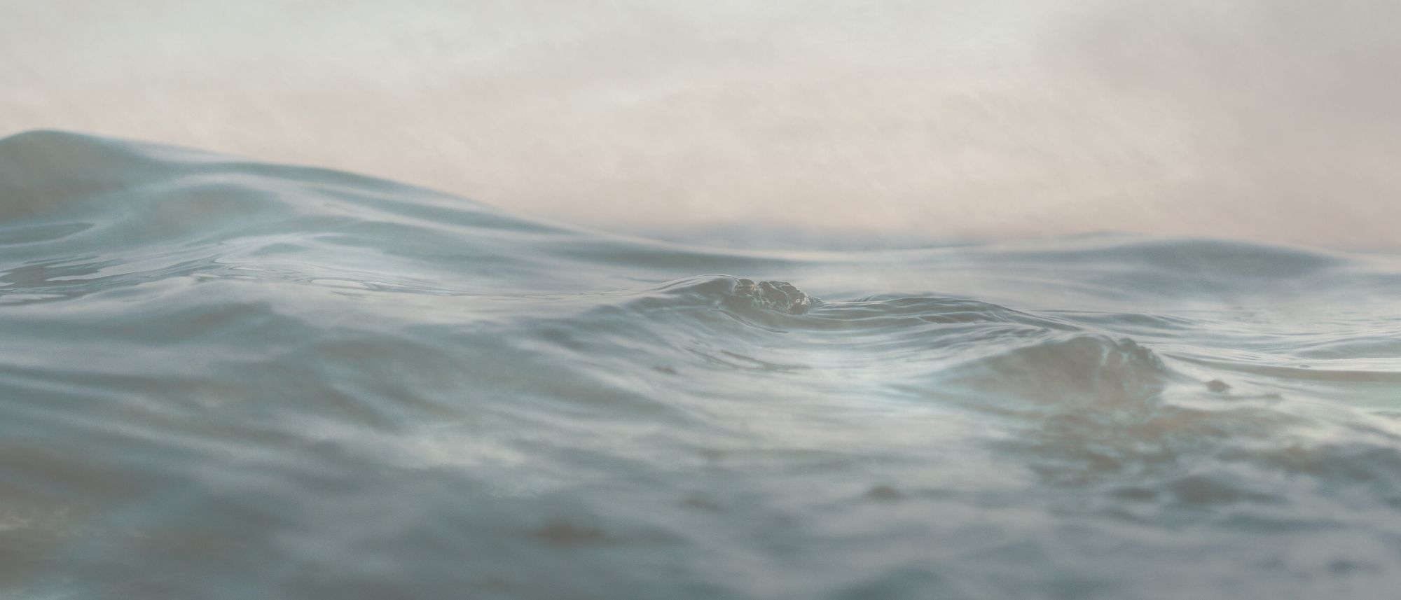 a photo of waves that is overlaid with a bit on transparency on a photo of hazy clouds.